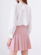 the back view of a lady in pink pleated skirt with blouse